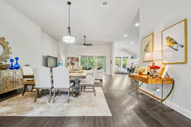 a living room with furniture and a dining table with wooden floor
