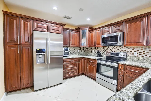 a kitchen with stainless steel appliances granite countertop a refrigerator and a stove top oven
