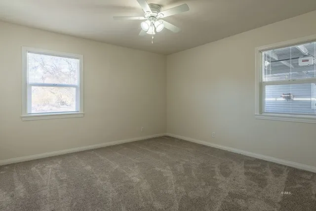 an empty room with a window and a fan