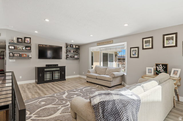 114 North Clark Lane Elk Ridge, UT 84651 - Photo 4 of 26 Open-concept living space featuring wood-finish flooring, recessed lighting, a bay window, and a built-in media console