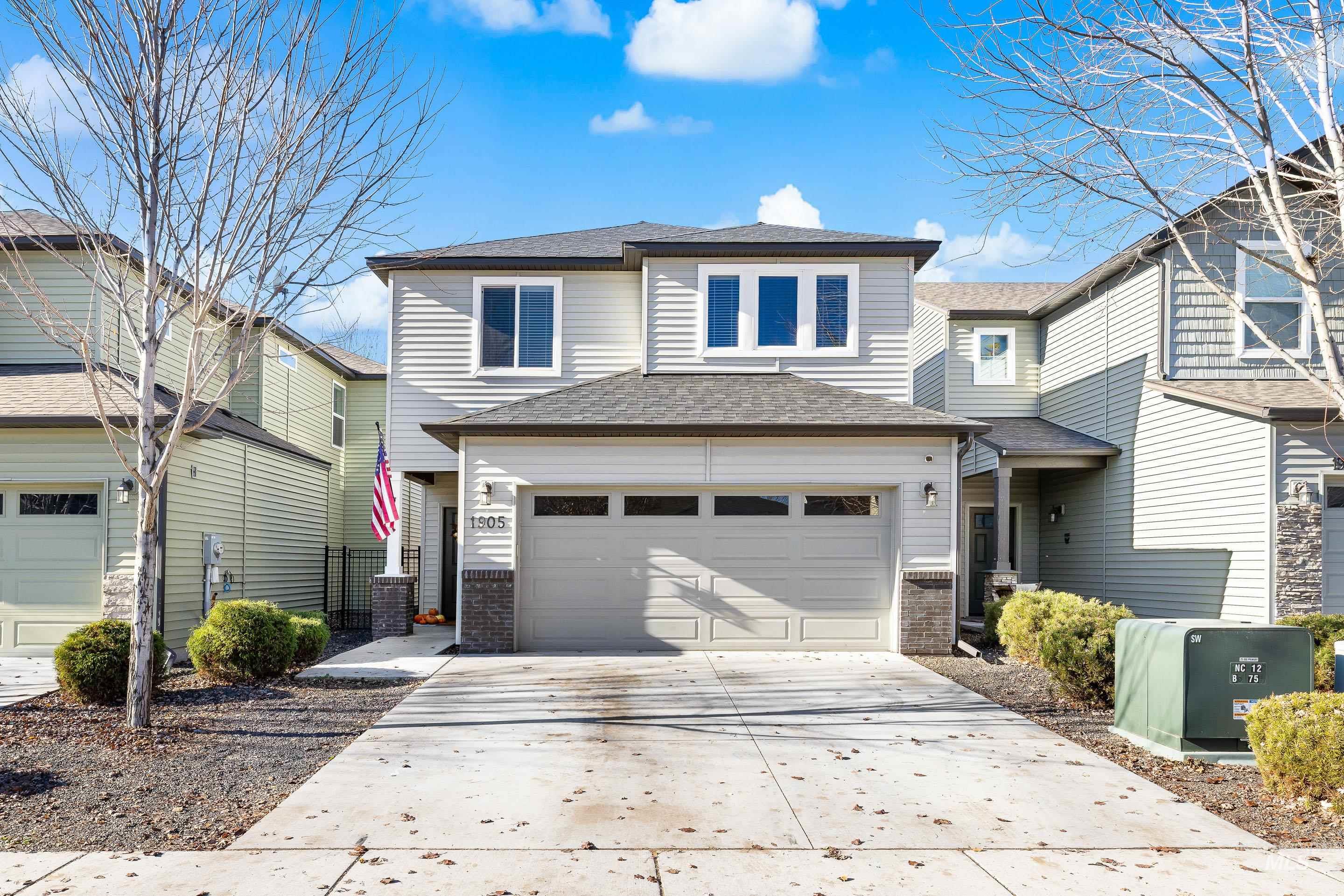 View of front of home featuring a shingled roof, concrete driveway, brick siding, and an attached garage