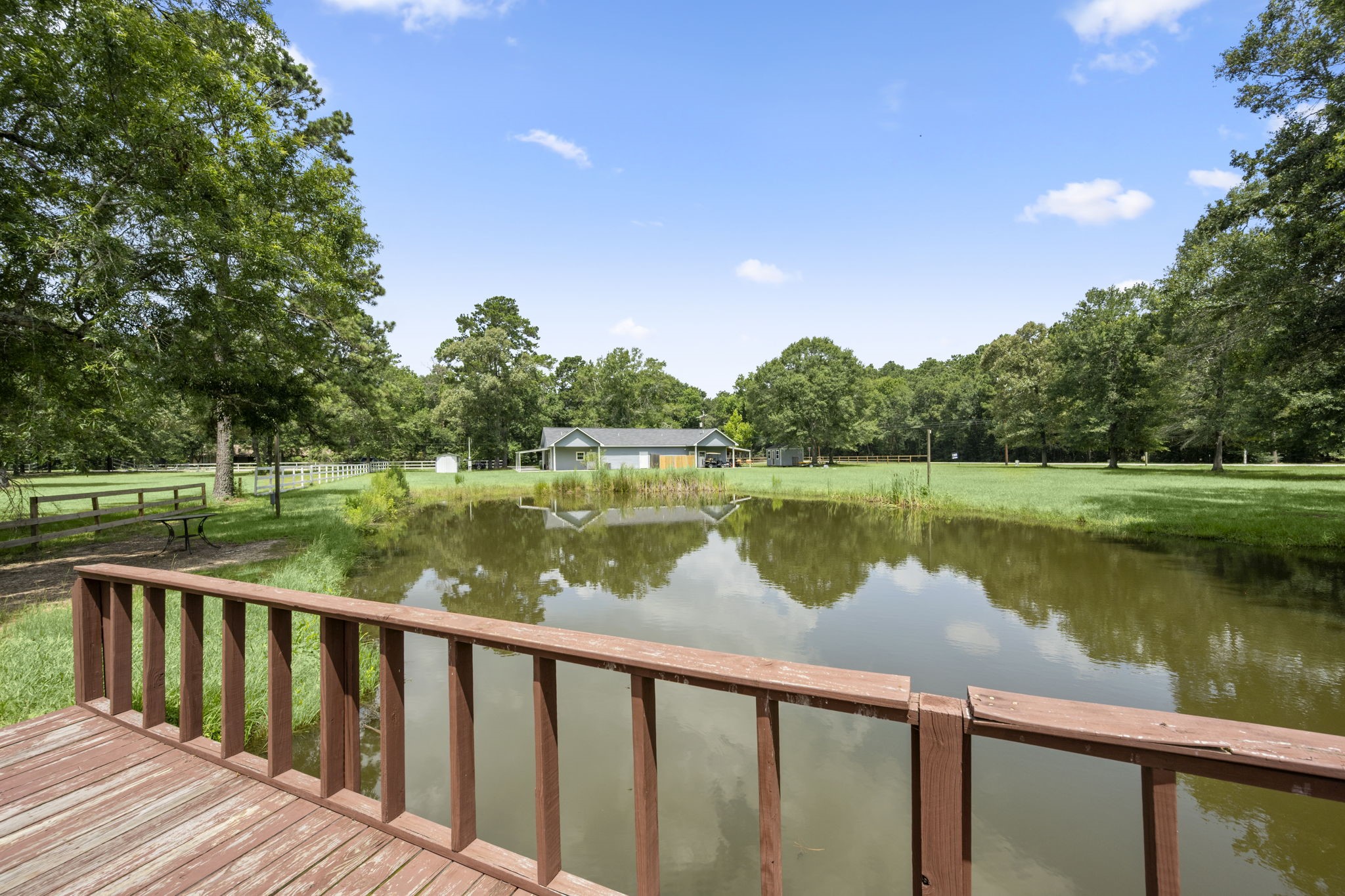 10871 Coaster Lane Conroe, TX 77306 - Photo 29 of 37 Standing on the bridge overlooking the stocked pond looking back towards the house. This pond is stocked with catfish and have been hand fed by the owner. Nice shaded area to the left with power pole.