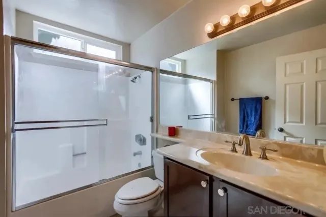 a bathroom with a granite countertop sink toilet and shower