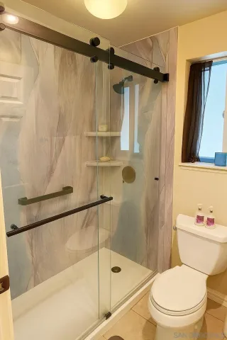 a white toilet sitting next to a bath tub and a shower