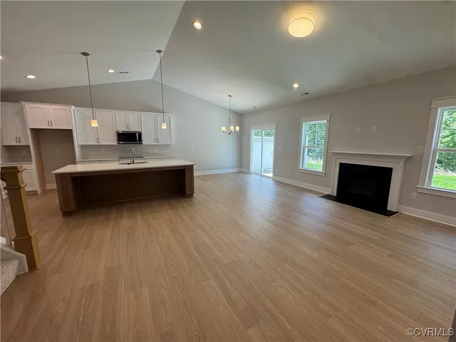 a large white kitchen with a large window a stove and a wooden floor