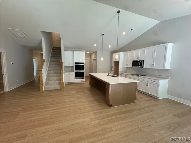 a large kitchen with stainless steel appliances kitchen island granite countertop a large counter top and a stove top oven