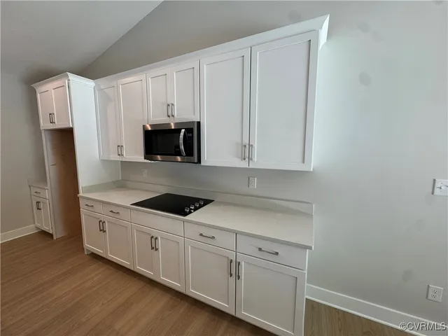 a kitchen with granite countertop white cabinets and refrigerator