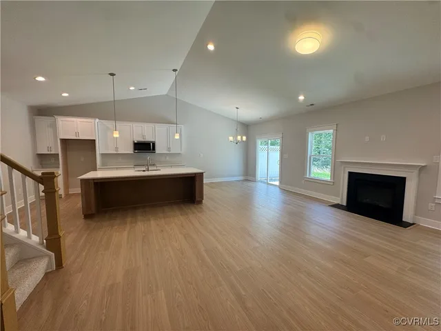 a large kitchen with stainless steel appliances a large counter top a wooden floors and a fireplace