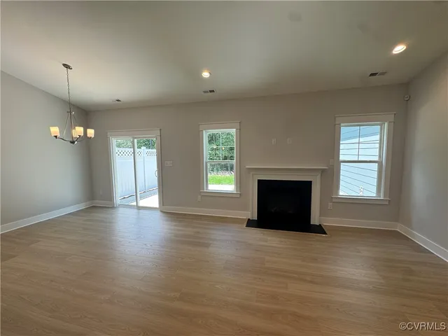 an empty room with wooden floor fireplace and windows