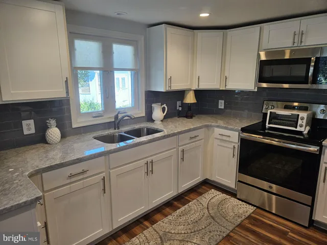 a kitchen with stainless steel appliances granite countertop a sink a stove and a microwave