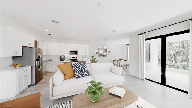 a living room with stainless steel appliances furniture and a large window