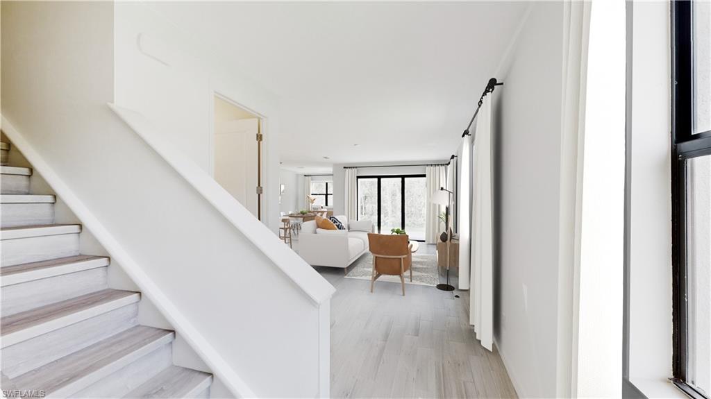 3089 Juniper Way Naples, FL 34112 - Photo 9 of 28 a hallway with wooden floor and furniture