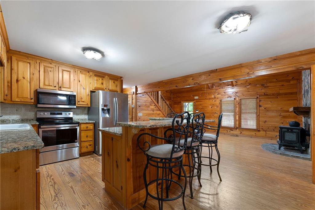 442 Cartecay River Run Ellijay, GA 30536 - Photo 15 of 63 a kitchen with stainless steel appliances granite countertop a stove top oven a refrigerator a dining table and chairs with wooden floor