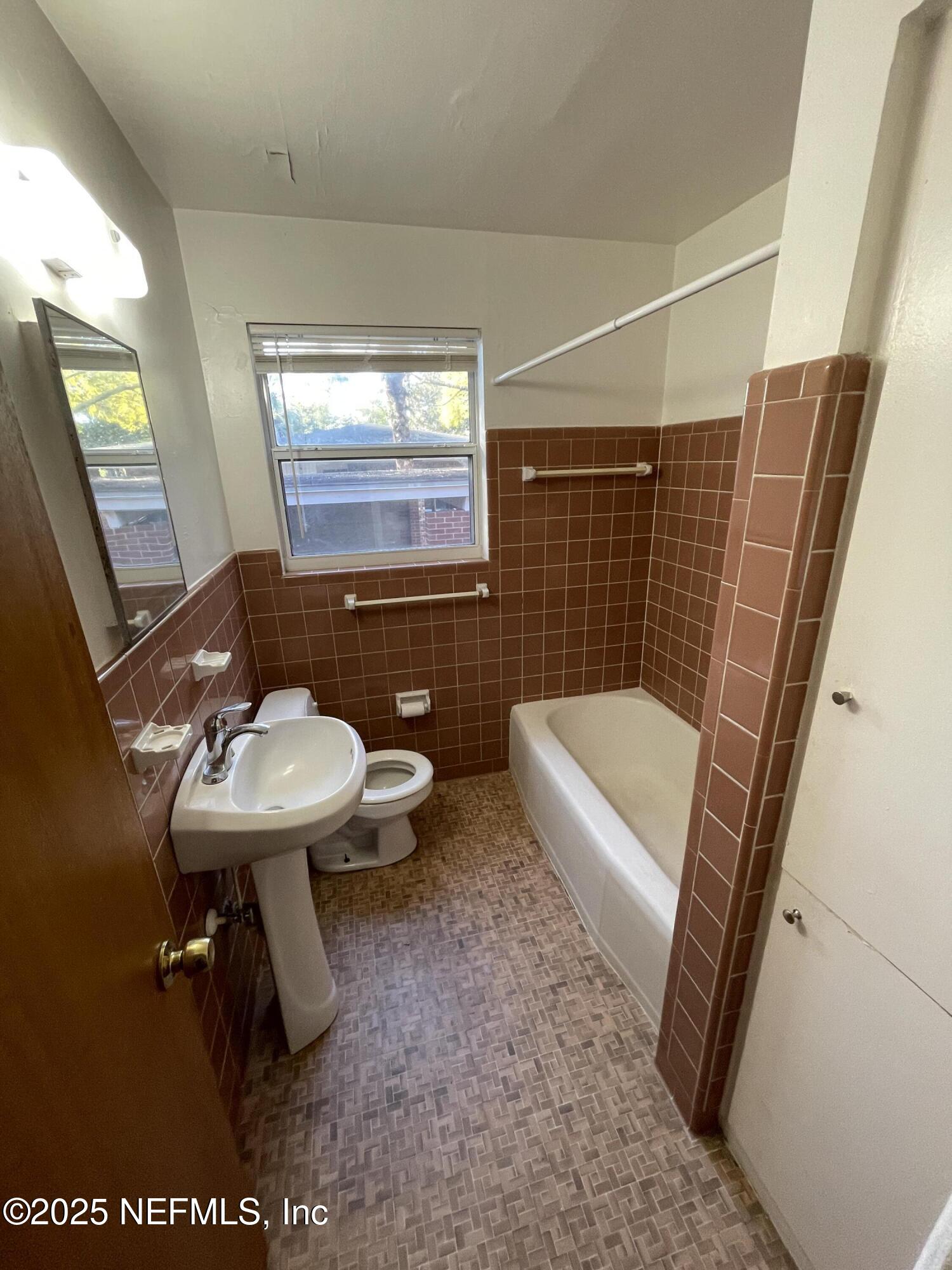 5452 Santa Rosa Way, Unit 4 Jacksonville, FL 32211 - Photo 4 of 6 a bathroom with a sink a toilet a mirror and shower