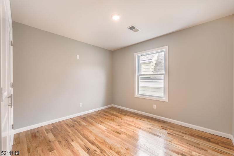 255 Chadwick Avenue, Unit 2 Newark, NJ 07108 - Photo 13 of 23 an empty room with wooden floor and windows