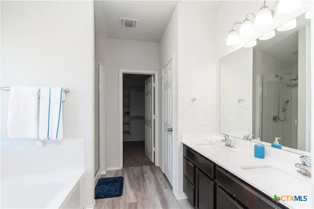 a spacious bathroom with a double vanity sink a mirror and a shower