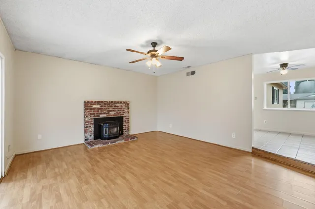 a view of empty room with a fireplace and a ceiling fan