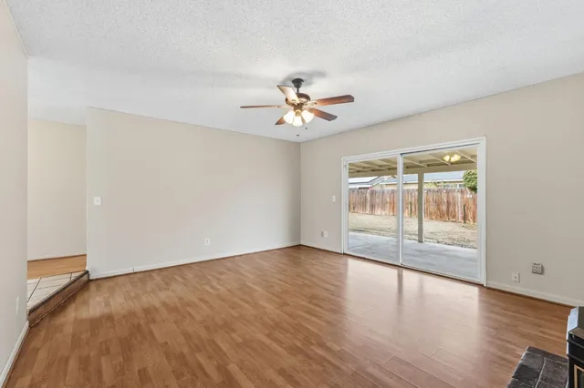 an empty room with wooden floor and chandelier fan