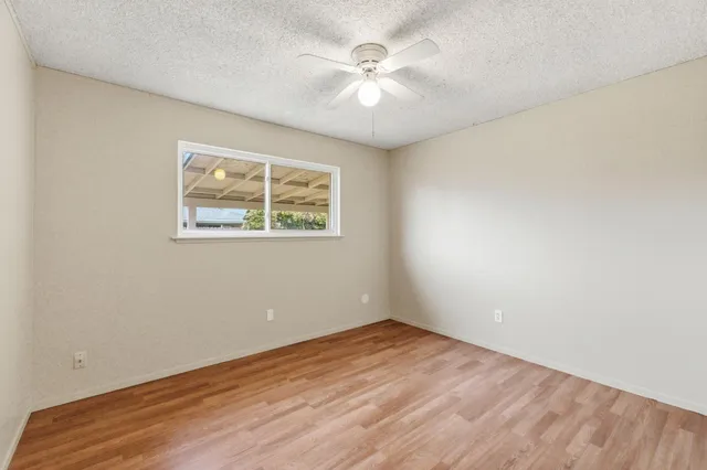 an empty room with a window and a fan