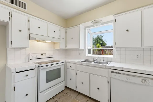 a kitchen with white cabinets appliances and a window