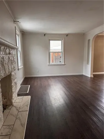 an empty room with wooden floor a fireplace and windows