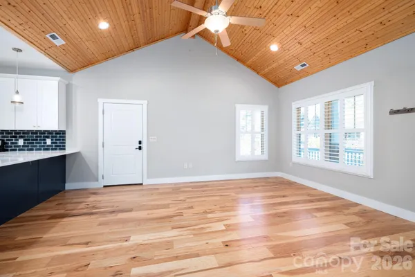 a view of an empty room with window and wooden floor
