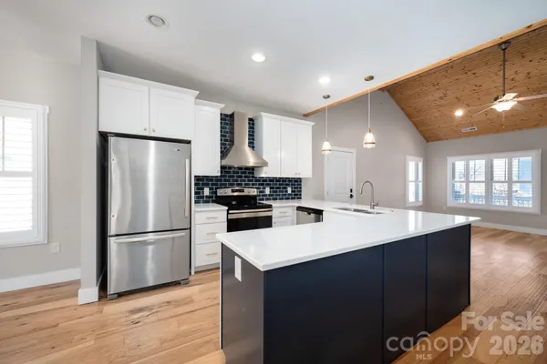 a kitchen with a sink a refrigerator and wooden floor