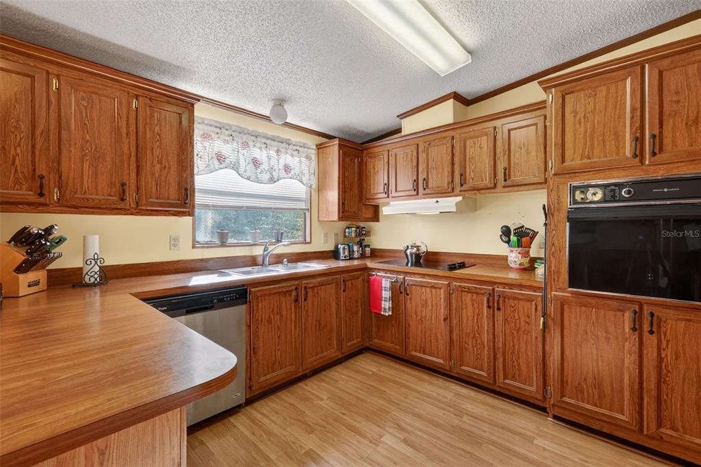 11911 Lane Park Road Tavares, FL 32778 - Photo 10 of 30 a kitchen with kitchen island granite countertop wooden cabinets a sink and dishwasher