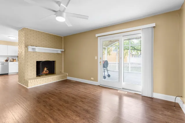 an empty room with wooden floor fireplace and windows