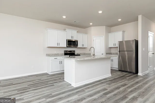 a kitchen with a refrigerator cabinets and wooden floor
