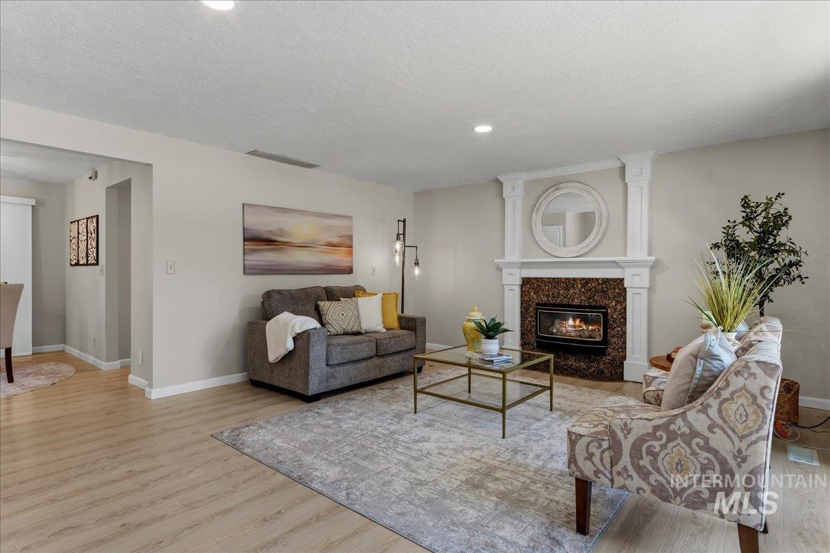 599 Pebble Beach Way Eagle, ID 83616 - Photo 16 of 44 Living area featuring a fireplace with a stone surround, decorative mantel, and light wood-finish flooring