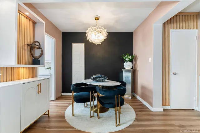 a dining room with wooden floor a chandelier a wooden table and chairs