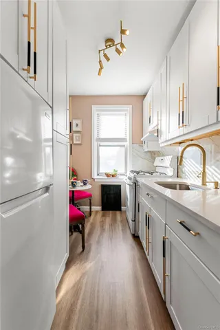 a kitchen with a refrigerator a sink dishwasher and a stove with wooden floor