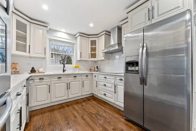a kitchen with stainless steel appliances granite countertop a refrigerator sink and white cabinets