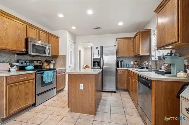 a kitchen with stainless steel appliances granite countertop a stove top oven a sink dishwasher and a refrigerator