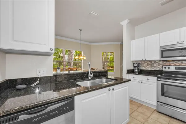 a kitchen with granite countertop stainless steel appliances a sink window and cabinets