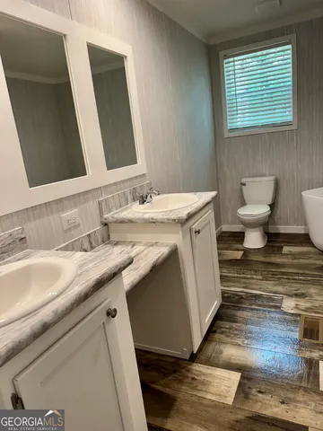 a bathroom with a granite countertop sink toilet and mirror
