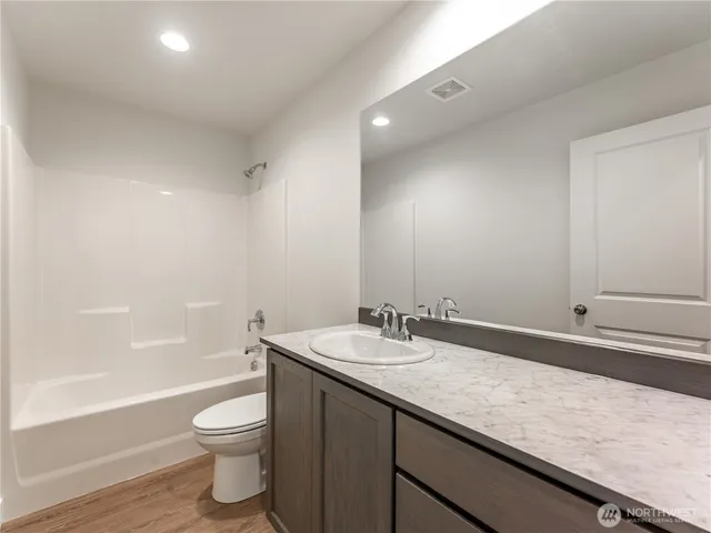 a bathroom with a granite countertop sink a toilet and bathtub