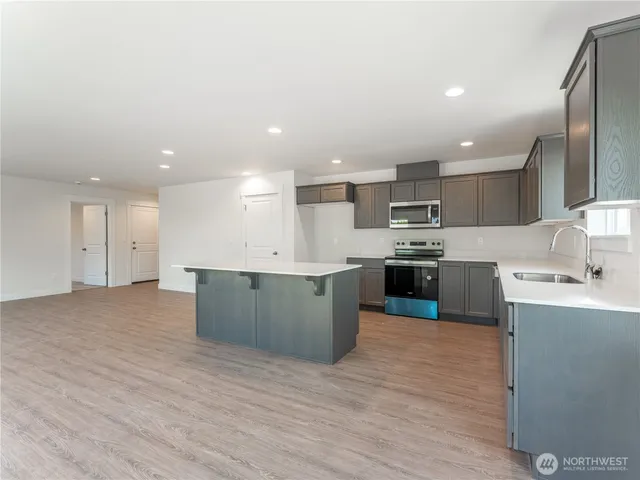 a large kitchen with a large counter top a sink stainless steel appliances and cabinets