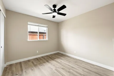 an empty room with ceiling fan and window
