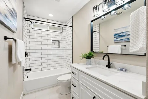 a bathroom with a sink a toilet a mirror a vanity and bathtub