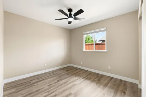 an empty room with ceiling fan and window