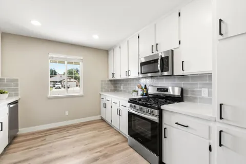 a kitchen with stainless steel appliances granite countertop a stove a sink and a microwave