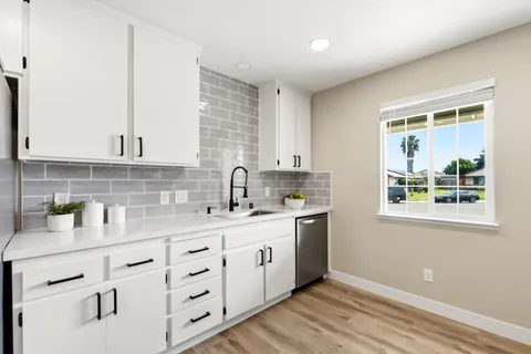 a kitchen with cabinets appliances a sink and a window