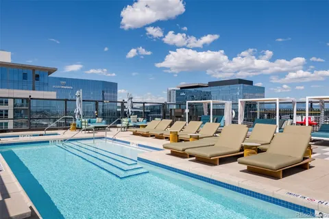 a view of pool with lawn chairs and floor to ceiling window