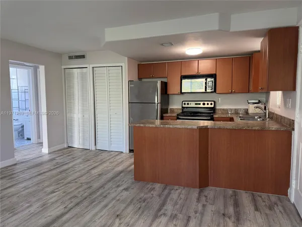 a kitchen with stainless steel appliances granite countertop a refrigerator a stove and a wooden floors