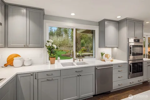 a kitchen with stainless steel appliances granite countertop a sink a stove and a wooden floors