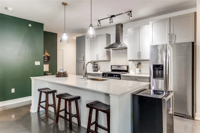 a kitchen with stainless steel appliances a sink a stove a refrigerator and island