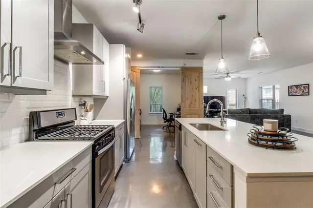 a kitchen with kitchen island a stove a sink a refrigerator and chairs