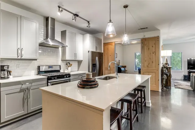 a kitchen with a stove a refrigerator a sink a dining table and chairs with wooden floor